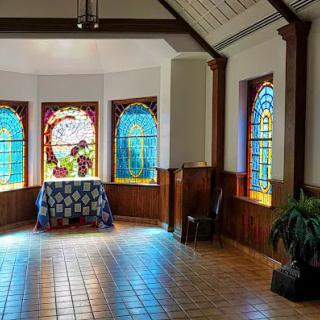 A bright room featuring stained glass windows casting colorful light inside.