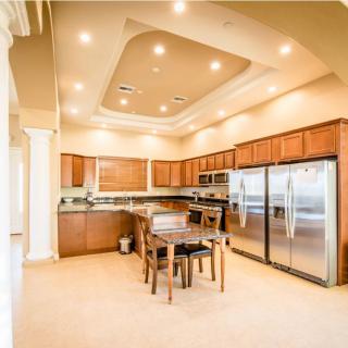 A spacious and modern kitchen with wooden cabinetry, stainless steel appliances, and a dining area under recessed lighting.