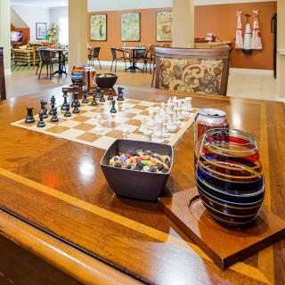A cozy game room featuring a chess set on a polished wooden table, surrounded by decorative elements.