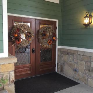 Decorated front entrance with wreaths and lighting.