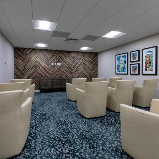 A modern waiting room with comfortable armchairs and artwork on the walls.