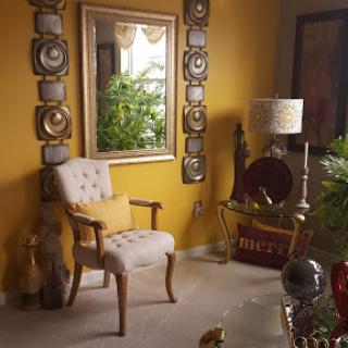 A cozy living room corner featuring a stylish chair, decorative mirror, and vibrant yellow walls.