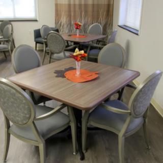 An indoor dining area with neatly arranged tables and chairs, featuring decorative centerpieces.