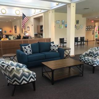 A lobby with a comfortable seating area featuring a sofa, armchairs, and a coffee table.