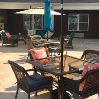 A sunny outdoor patio featuring tables and chairs with colorful cushions and umbrellas.