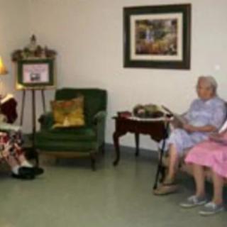 Two seniors sitting in a living room setting, one reading a book.