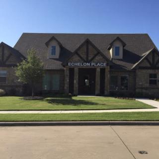 A suburban house with a well-maintained lawn under a clear blue sky.