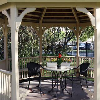 An inviting gazebo with a table and chairs set in a tranquil garden setting.