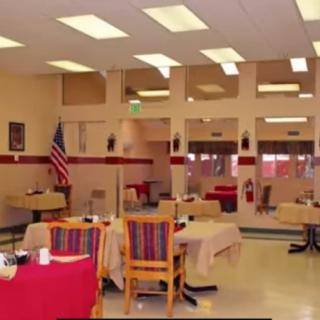 An empty dining area with tables and chairs, decorated with an American flag and indoor lighting.