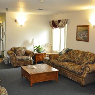 A cozy living room with patterned sofas, an armchair, and a wooden coffee table.