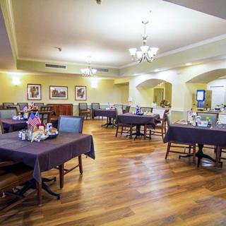 A spacious and elegantly decorated dining area with neatly arranged tables and chairs, featuring warm lighting and tasteful decor.