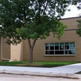 A school building with trees and a sidewalk in front.