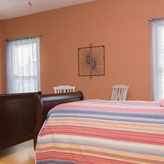 A cozy bedroom with a striped bedspread and warm-toned walls.
