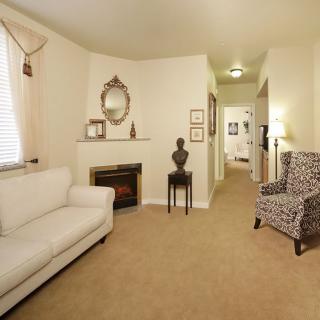 A cozy living room with a white couch, patterned armchair, and decorative fireplace.