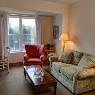 A cozy living room with a floral-patterned sofa and a red armchair near a window.