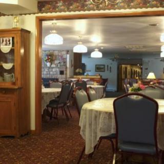 A cozy dining room with tables and chairs arranged neatly under warm lighting.
