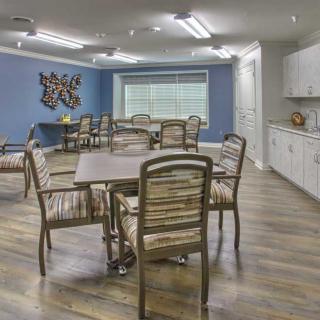 A dining area featuring multiple tables and chairs, a kitchenette, and a blue accent wall.