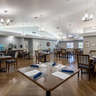 A spacious dining area with neatly arranged tables, chairs, and elegant chandeliers.