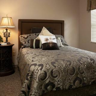 A cozy and elegantly decorated bedroom featuring a stylish bed with intricate bedding and a bedside lamp.