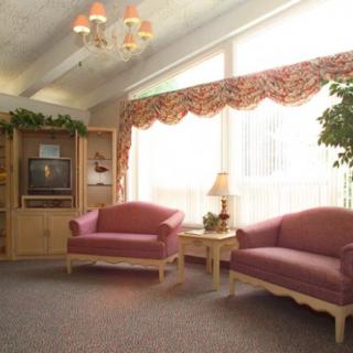 A cozy living room with two sofas, a television, and a large window with curtains.