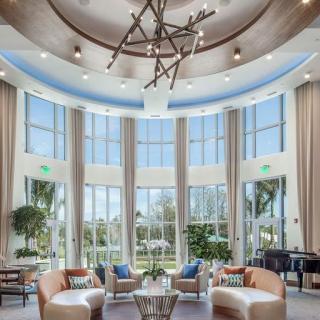 A luxurious living room with modern design elements, featuring large windows, a chandelier, and comfortable seating.
