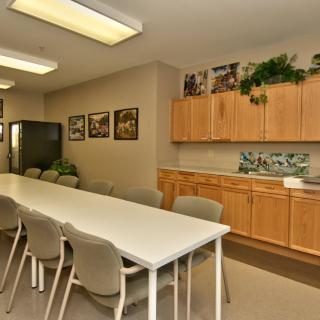 A well-lit conference room with a long table, several chairs, and cabinetry along the wall.