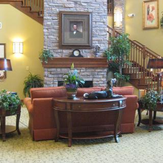 A cozy living room setting with a red sofa, wooden coffee table, and a stone fireplace, adorned with plants and decorative items.