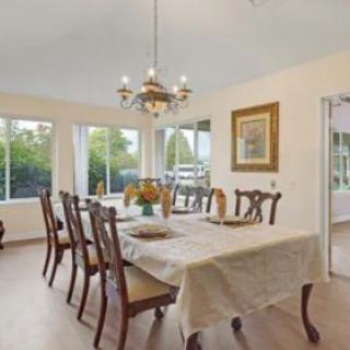A bright and elegant dining room with a chandelier, table, and chairs, complemented by large windows.