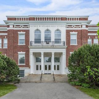 A historic brick building with an elegant entrance and stairs, likely part of a college or university campus.