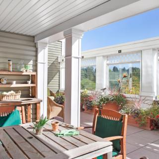 A cozy outdoor patio with wooden furniture, plants, and a sunny setting.