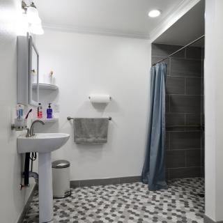 A modern bathroom with a sink, shower, and patterned tile flooring.