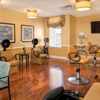 A cozy salon interior with chairs and hair dryers, featuring warm lighting and a wooden floor.