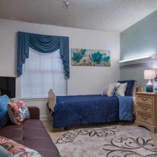 A cozy bedroom featuring a blue color scheme with floral accents and a comfortable seating area.