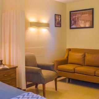 A cozy living space featuring a brown sofa, a comfortable chair, and subtle wall lighting.