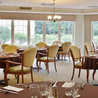 Elegant dining room with neatly arranged tables and chairs, illuminated by natural light through large windows.