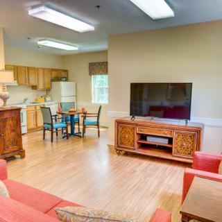 A cozy living space with a kitchen and dining area, featuring a comfortable sofa and a large TV.