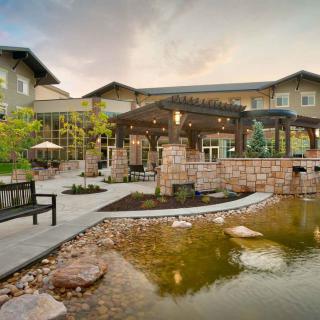 A serene outdoor patio area with a pond and garden landscaping in front of a modern building.