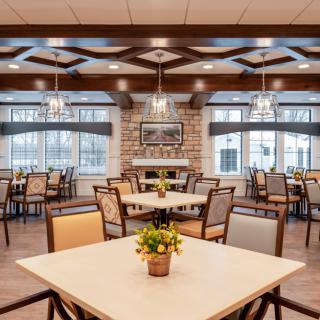 A spacious and elegantly designed dining room with neatly arranged tables and chairs, featuring large windows and modern lighting.