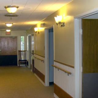 A well-lit hallway with doors on either side and handrails along the walls.