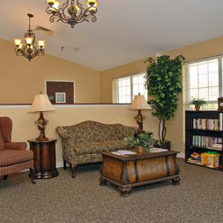 A cozy living room with comfortable furniture, warm lighting, and a bookshelf.