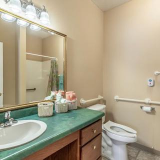A clean and simple bathroom with a green countertop and large mirror.