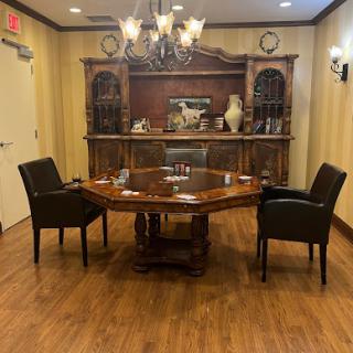 A well-furnished conference room featuring a round wooden table, black chairs, and an elegant chandelier.
