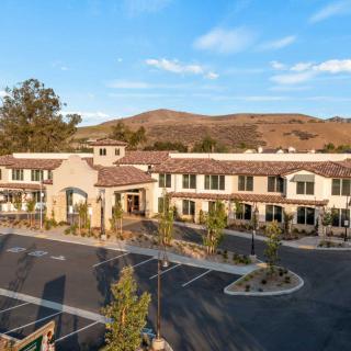 A modern building with a parking lot set against a scenic landscape and a clear blue sky.