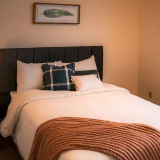 A cozy bedroom featuring a neatly made bed with pillows and a textured blanket.