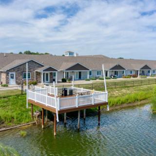 A series of waterfront residential buildings with a deck overlooking the lake under a cloudy sky.