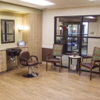 A well-lit salon interior with chairs, a mirror, and a neatly arranged waiting area.