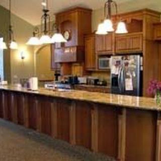 A spacious kitchen featuring wooden cabinetry, granite countertops, and modern pendant lighting.