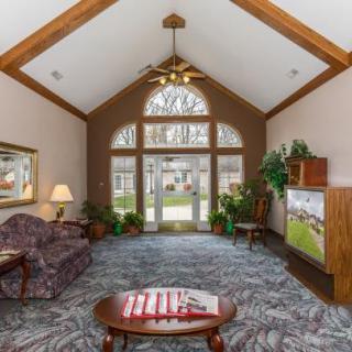 Cozy living room with vaulted ceiling, featuring a sofa, table, and large windows.