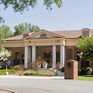 A residential building with classical columns surrounded by trees.