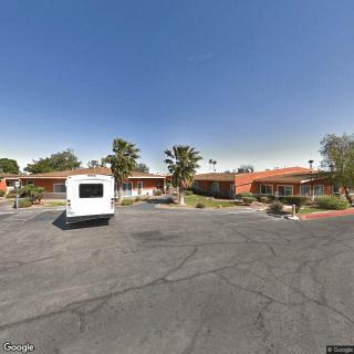 A roadside motel with a parked vehicle in a desert landscape under a clear blue sky.